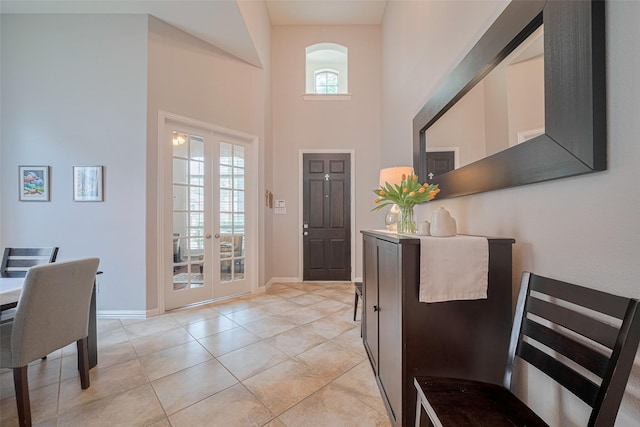 foyer entrance with a towering ceiling, french doors, baseboards, and light tile patterned flooring