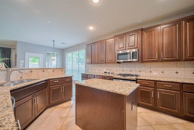 kitchen with appliances with stainless steel finishes, a sink, light tile patterned floors, decorative backsplash, and a kitchen island
