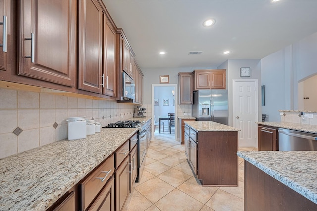 kitchen featuring stainless steel appliances, tasteful backsplash, light stone counters, recessed lighting, and light tile patterned floors
