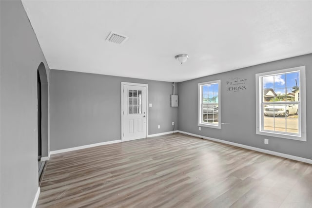 spare room with wood finished floors, baseboards, and arched walkways