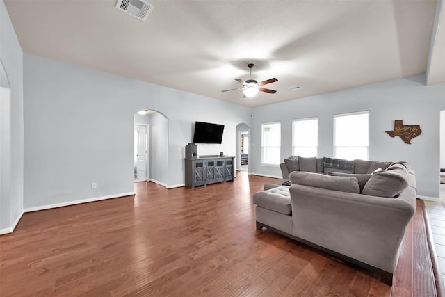 living room with arched walkways, ceiling fan, wood finished floors, and baseboards