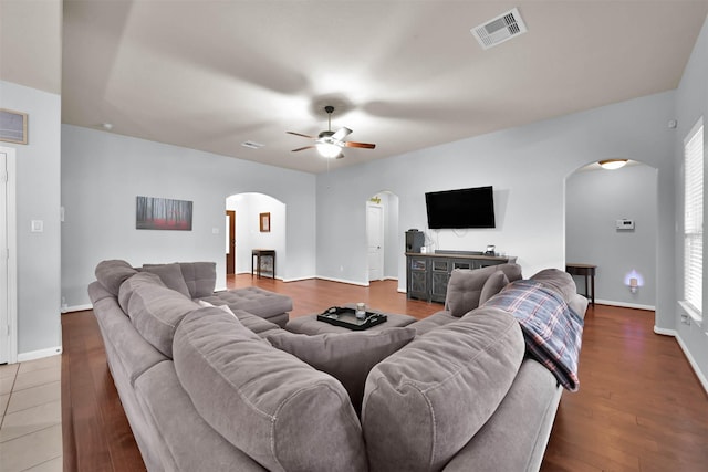 living room with arched walkways, a ceiling fan, baseboards, and wood finished floors