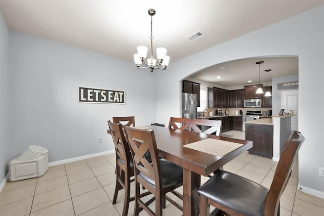 dining space featuring arched walkways, a chandelier, light tile patterned floors, baseboards, and recessed lighting