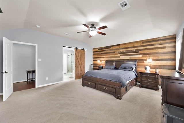 bedroom featuring lofted ceiling, wooden walls, light colored carpet, a barn door, and ceiling fan
