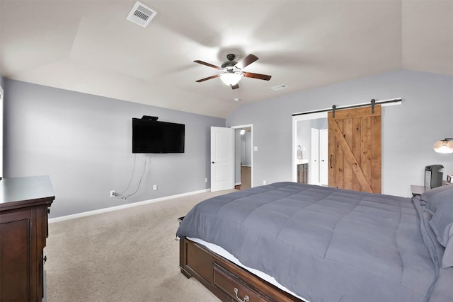 bedroom featuring light colored carpet, baseboards, a barn door, vaulted ceiling, and ensuite bathroom