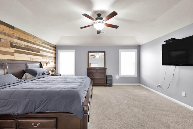 bedroom with wooden walls, baseboards, light carpet, and ceiling fan