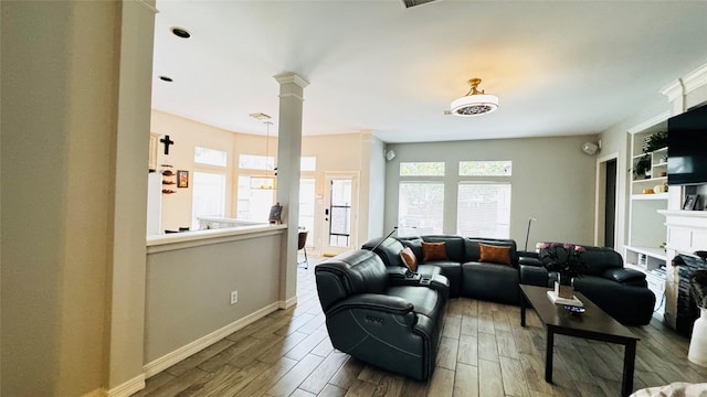 living room featuring wood finished floors, baseboards, and decorative columns