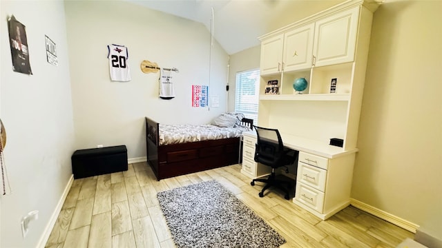 bedroom featuring lofted ceiling, light wood-type flooring, baseboards, and an office area