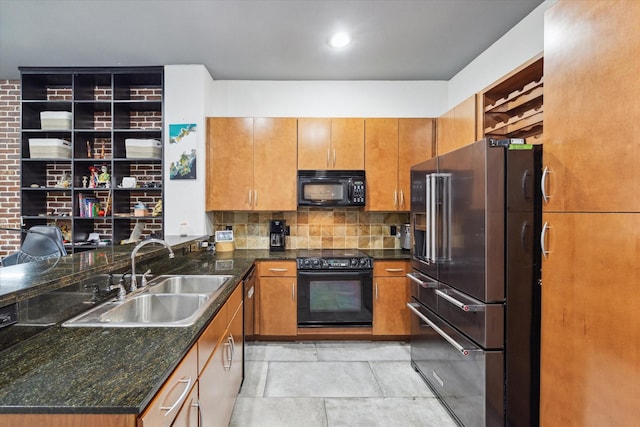 kitchen featuring black appliances, a sink, brown cabinets, decorative backsplash, and dark stone counters