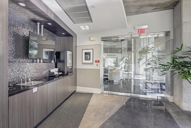 kitchen featuring a sink, dark countertops, modern cabinets, tasteful backsplash, and baseboards