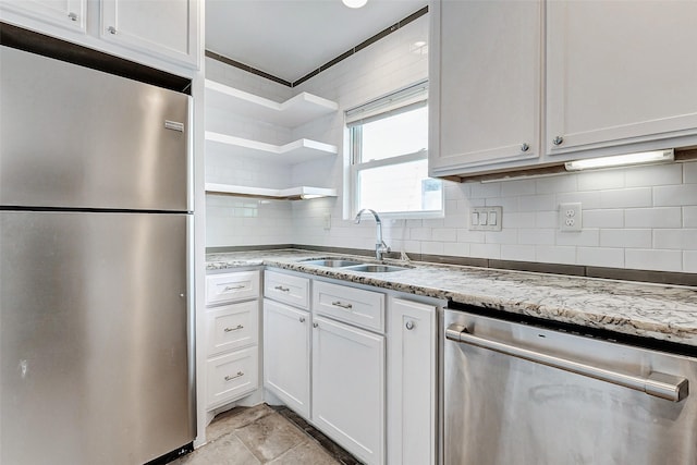 kitchen featuring stainless steel appliances, a sink, tasteful backsplash, white cabinets, and light stone counters