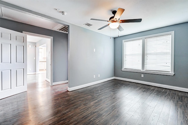 spare room with a ceiling fan, dark wood finished floors, baseboards, and attic access