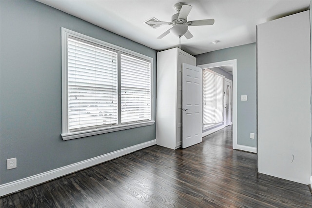 spare room with plenty of natural light, dark wood finished floors, ceiling fan, and baseboards