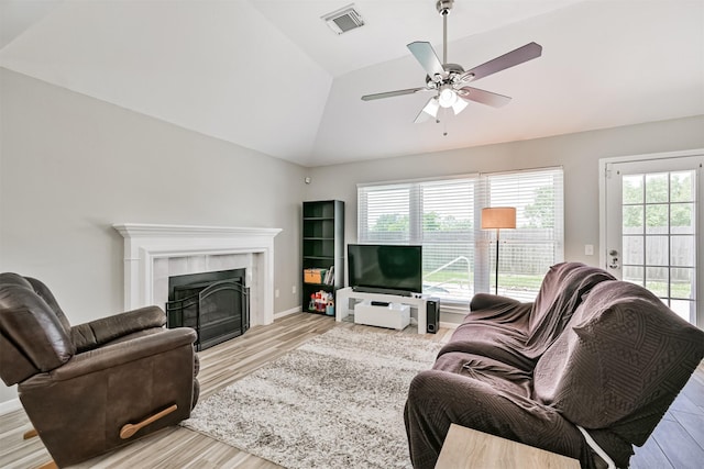 living room featuring plenty of natural light, light wood-type flooring, lofted ceiling, a fireplace, and ceiling fan