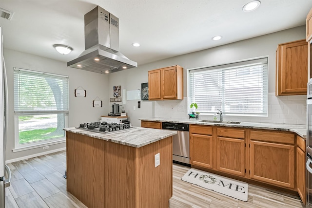 kitchen featuring island exhaust hood, a sink, appliances with stainless steel finishes, a kitchen island, and tasteful backsplash