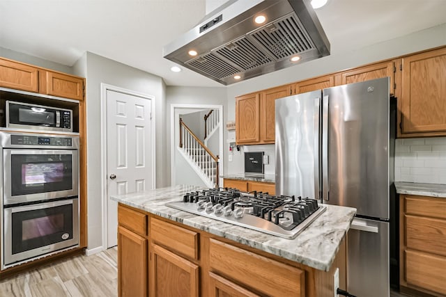 kitchen featuring stainless steel appliances, exhaust hood, tasteful backsplash, recessed lighting, and light stone countertops