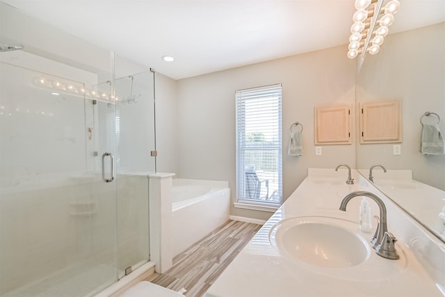 bathroom with wood finished floors, a bath, a stall shower, and double vanity