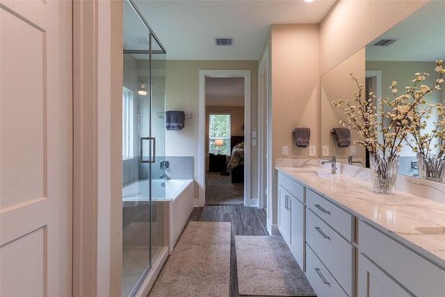 ensuite bathroom with wood finished floors, a shower stall, double vanity, and a bath