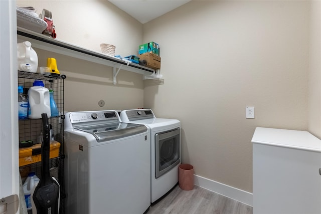 laundry area featuring independent washer and dryer, light wood-style floors, and baseboards