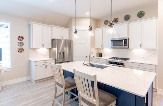 kitchen with stainless steel appliances, a sink, a kitchen bar, tasteful backsplash, and vaulted ceiling