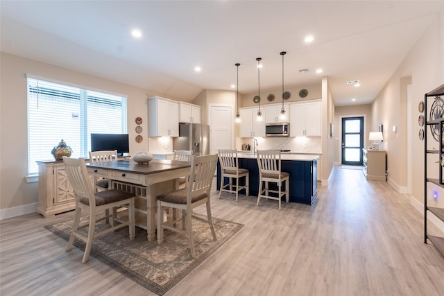 dining area with baseboards and light wood finished floors