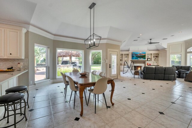 12710 Everhart Pointe Dr, Tomball, TX 77377 - dining area featuring light tile patterned floors, crown molding, a lit fireplace, built in shelves, and ceiling fan