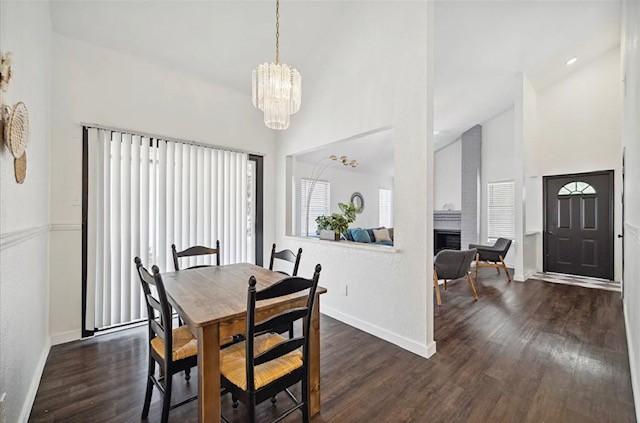 3734 Varla Ln, Houston, TX 77014 - dining room featuring high vaulted ceiling, dark wood-style floors, a chandelier, baseboards, and a fireplace