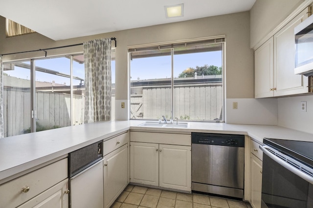 kitchen with appliances with stainless steel finishes, healthy amount of natural light, a sink, and light tile patterned floors
