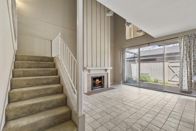 stairway featuring a towering ceiling and a tile fireplace