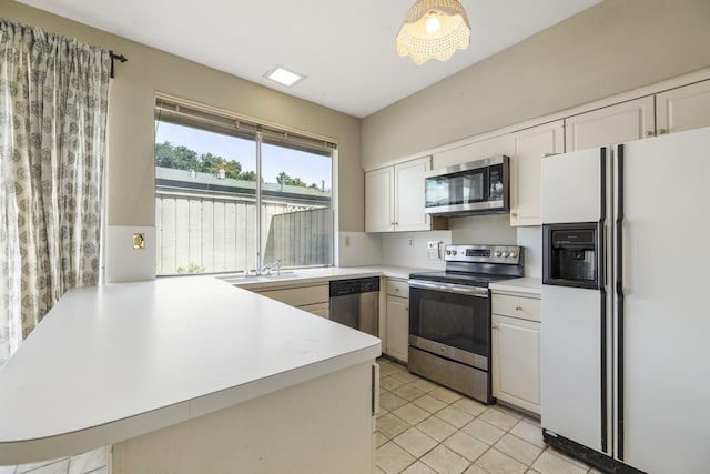 kitchen with appliances with stainless steel finishes, a peninsula, light countertops, a sink, and light tile patterned floors