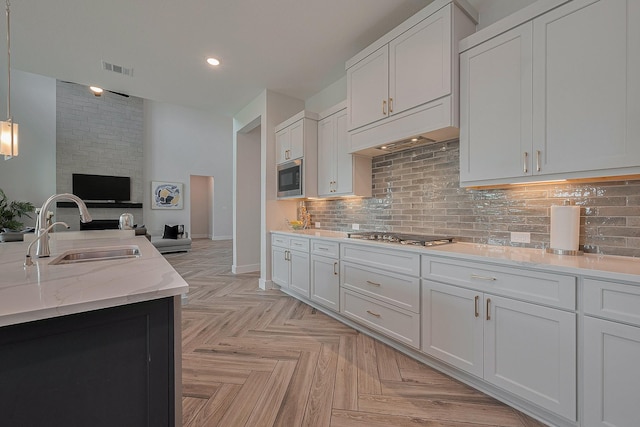 27807 Bridgeway St, Spring, TX 77386 - kitchen featuring a sink, appliances with stainless steel finishes, white cabinetry, backsplash, and open floor plan
