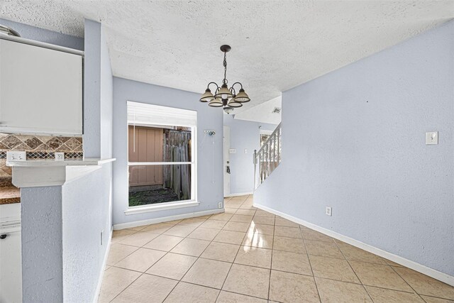 17607 Northfalk Dr, Houston, TX 77084 - unfurnished dining area featuring a chandelier, light tile patterned floors, baseboards, a textured ceiling, and stairway