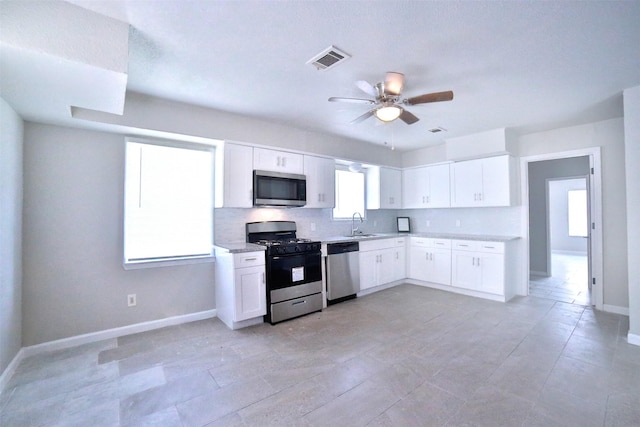 6534 Ledbetter St, Houston, TX 77087 - kitchen with appliances with stainless steel finishes, light countertops, a sink, white cabinetry, and ceiling fan