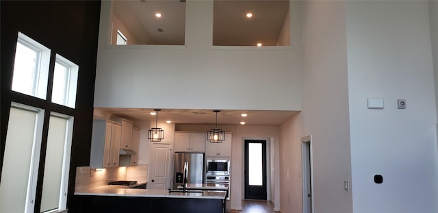 10611 Hidden Rock Dr, Missouri City, TX 77459 - kitchen with a high ceiling, stainless steel appliances, light countertops, a peninsula, and decorative light fixtures