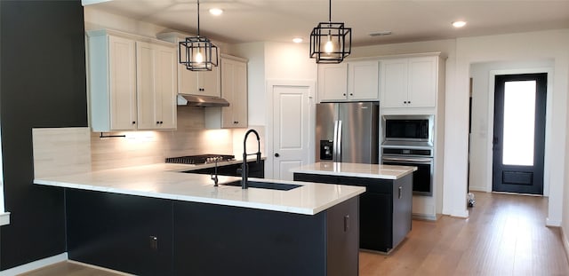 10611 Hidden Rock Dr, Missouri City, TX 77459 - kitchen featuring stainless steel appliances, under cabinet range hood, a peninsula, tasteful backsplash, and a sink
