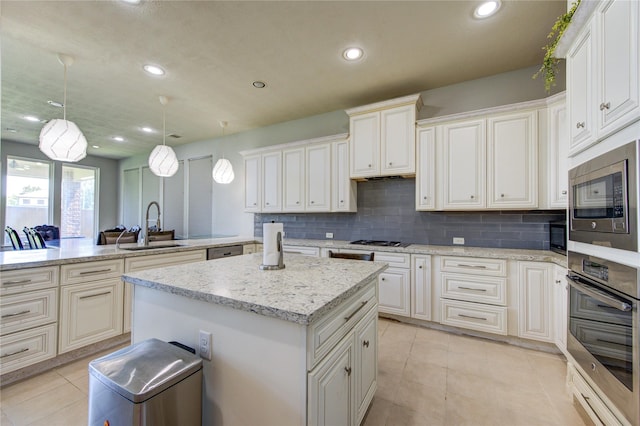 kitchen with stainless steel appliances, a sink, a center island, a peninsula, and decorative backsplash