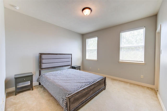 bedroom with light carpet and baseboards