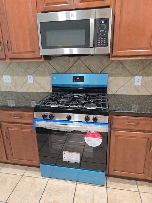 24911 Tribeca Ln, Katy, TX 77493 - kitchen featuring appliances with stainless steel finishes, tasteful backsplash, light tile patterned floors, and dark stone countertops
