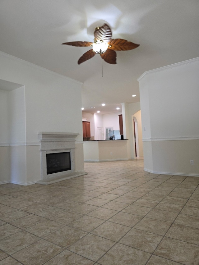24911 Tribeca Ln, Katy, TX 77493 - unfurnished living room featuring ceiling fan, crown molding, a fireplace with raised hearth, light tile patterned floors, and arched walkways