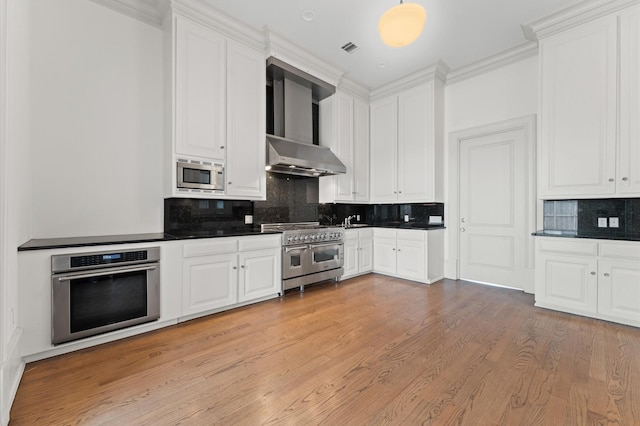 6104 San Felipe St, Houston, TX 77057 - kitchen featuring appliances with stainless steel finishes, wall chimney range hood, dark countertops, white cabinetry, and backsplash