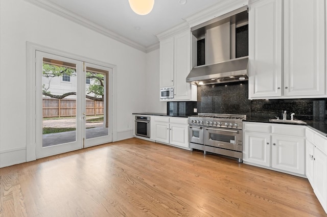 6104 San Felipe St, Houston, TX 77057 - kitchen featuring wall chimney range hood, appliances with stainless steel finishes, dark countertops, a sink, and crown molding