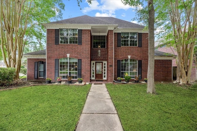 view of front of property with a front lawn, roof with shingles, and brick siding