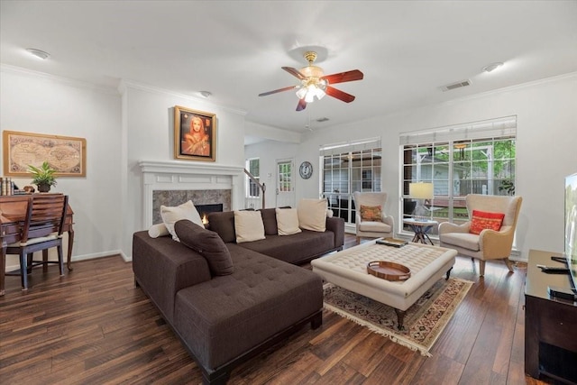 living room with dark wood-style floors, a ceiling fan, ornamental molding, a high end fireplace, and baseboards