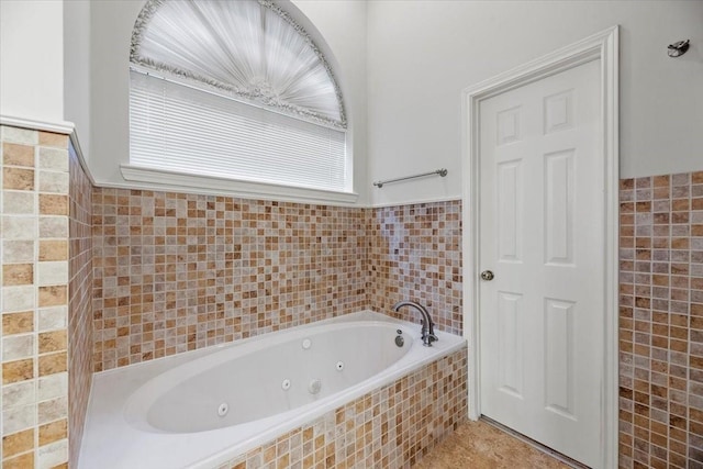 bathroom featuring tile walls, a tub with jets, and tile patterned floors