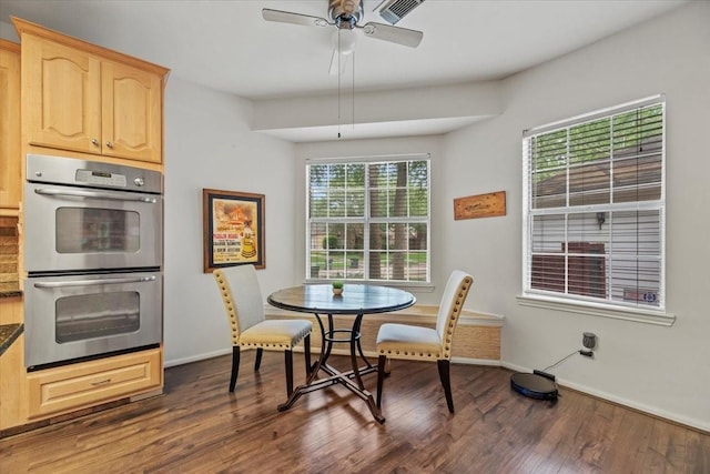 dining room with dark wood finished floors, a ceiling fan, and baseboards