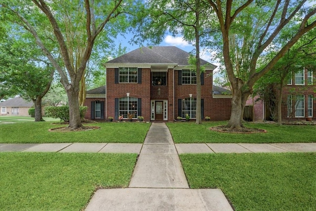 colonial-style house with brick siding, a front lawn, and a shingled roof