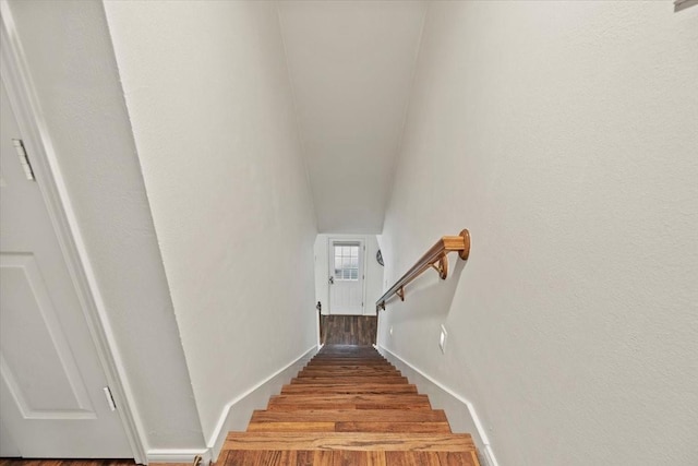 staircase featuring wood finished floors and baseboards