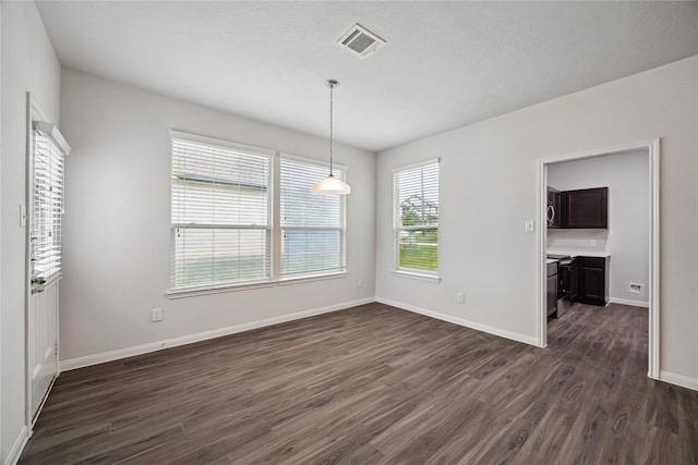 unfurnished dining area featuring dark wood finished floors and baseboards