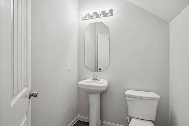 half bath featuring toilet and baseboards