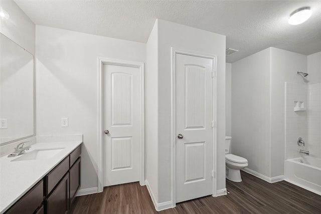 full bathroom featuring wood finished floors, toilet, vanity, a textured ceiling, and baseboards